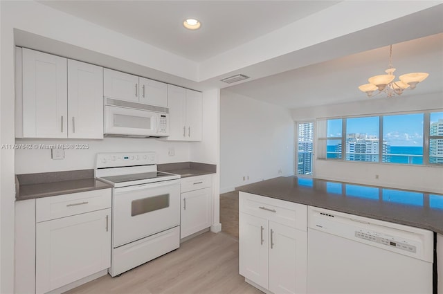 kitchen with white appliances, dark countertops, visible vents, and white cabinets