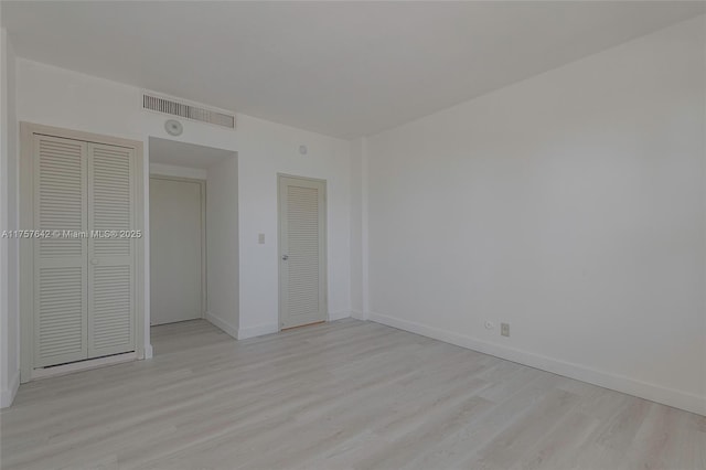 unfurnished bedroom with light wood finished floors, visible vents, and baseboards