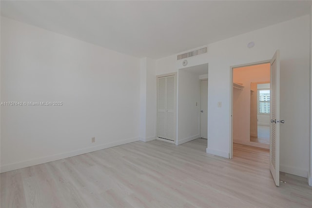 unfurnished bedroom with light wood finished floors, visible vents, and baseboards