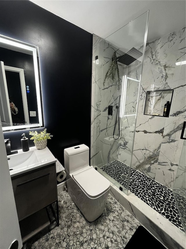 bathroom featuring a marble finish shower, toilet, and vanity