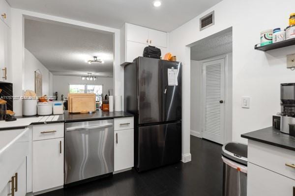 kitchen featuring visible vents, freestanding refrigerator, dark wood-type flooring, white cabinets, and stainless steel dishwasher