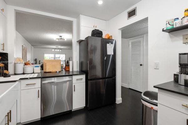 kitchen with visible vents, white cabinets, dishwasher, dark countertops, and freestanding refrigerator