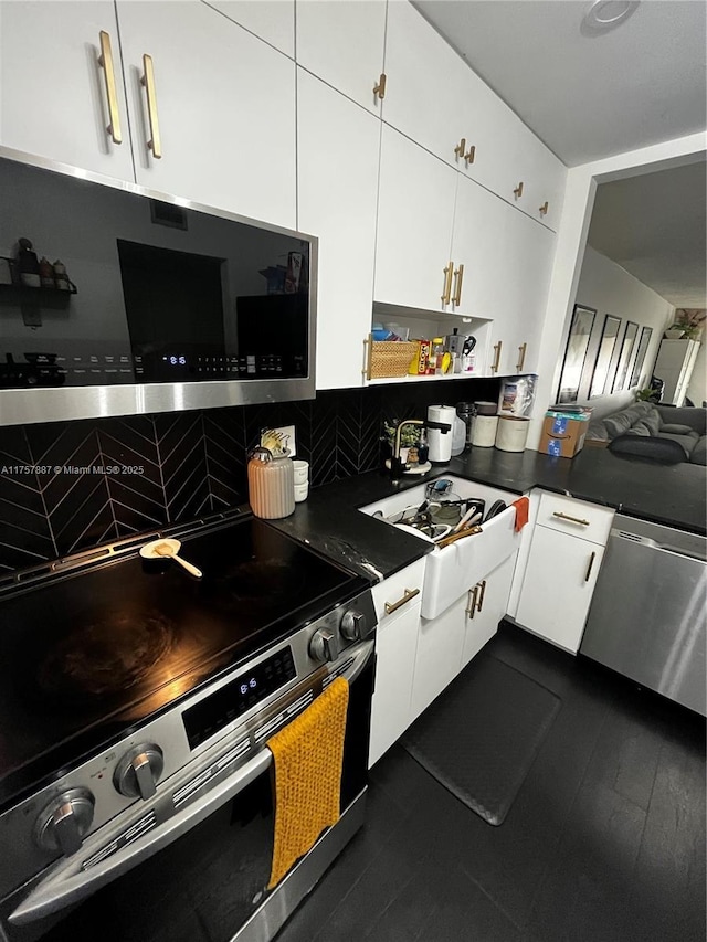 kitchen featuring dark countertops, white cabinets, appliances with stainless steel finishes, and a sink