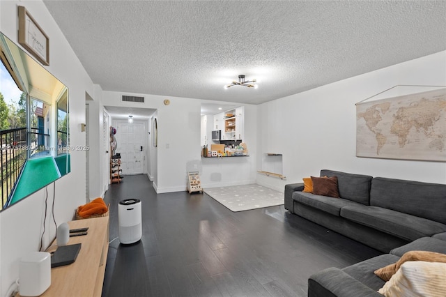 living area featuring baseboards, wood finished floors, visible vents, and a textured ceiling