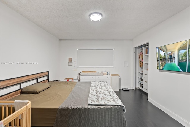 bedroom with a textured ceiling, dark wood-style flooring, and baseboards