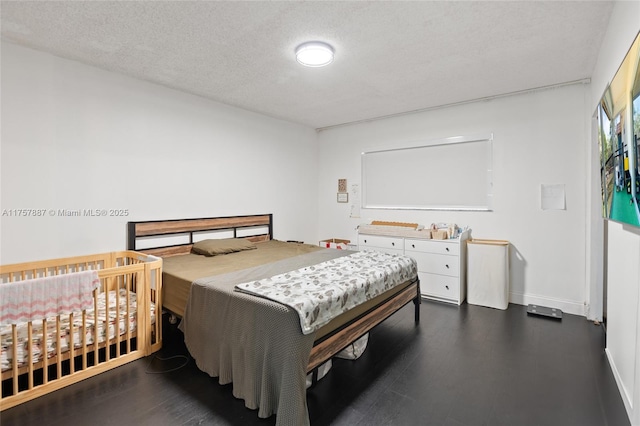 bedroom with a textured ceiling and dark wood-style floors