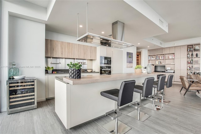 kitchen featuring beverage cooler, a breakfast bar, visible vents, stainless steel microwave, and modern cabinets