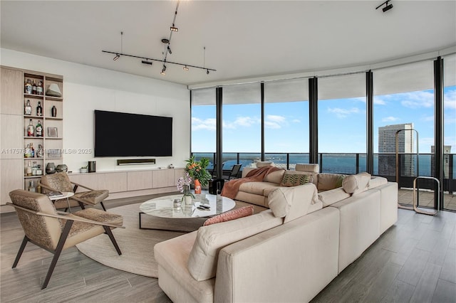 living room featuring a wall of windows, rail lighting, and wood finished floors