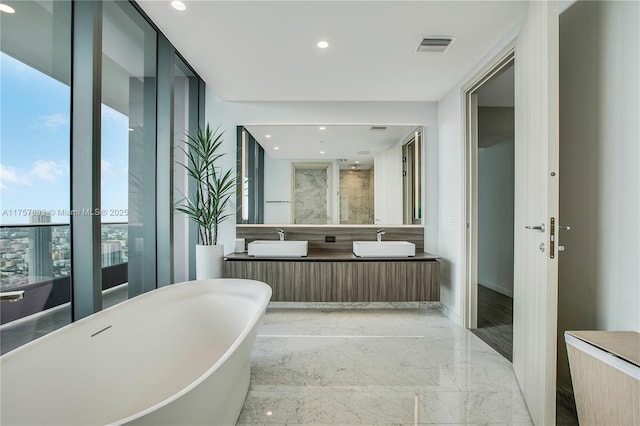 full bath featuring a sink, a freestanding bath, marble finish floor, and recessed lighting