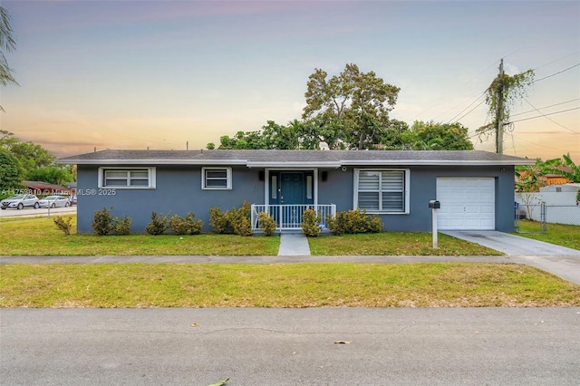 single story home with a garage, a front yard, fence, and stucco siding