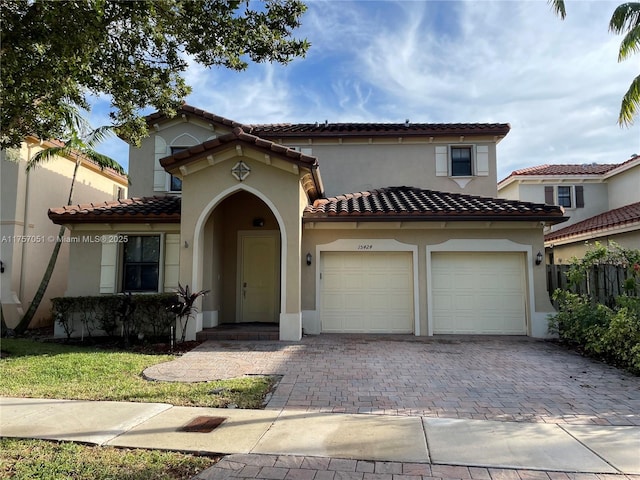 mediterranean / spanish-style home featuring decorative driveway, a tile roof, and stucco siding