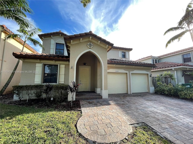 mediterranean / spanish house featuring a tiled roof, decorative driveway, and stucco siding