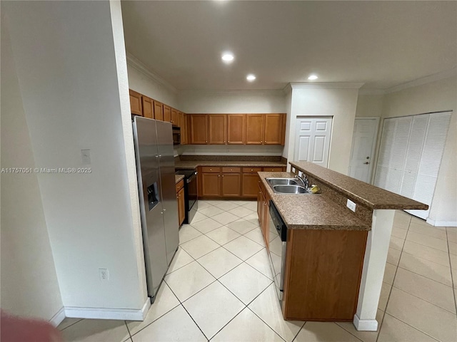 kitchen with dark countertops, ornamental molding, a kitchen island with sink, a sink, and black appliances