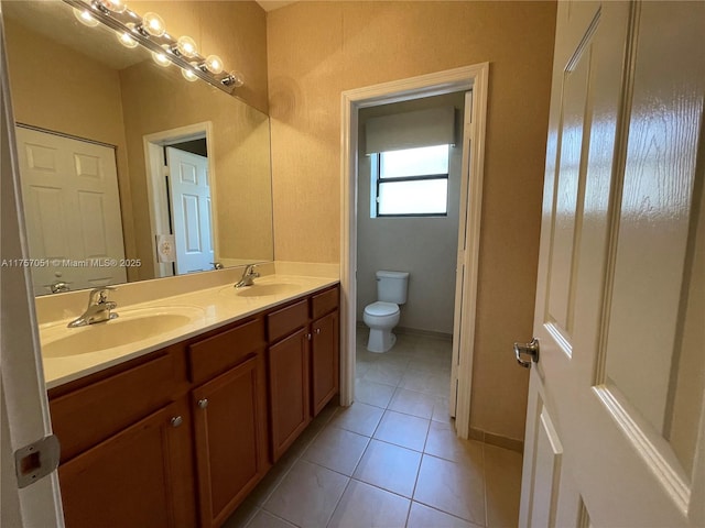 bathroom with toilet, tile patterned flooring, double vanity, and a sink