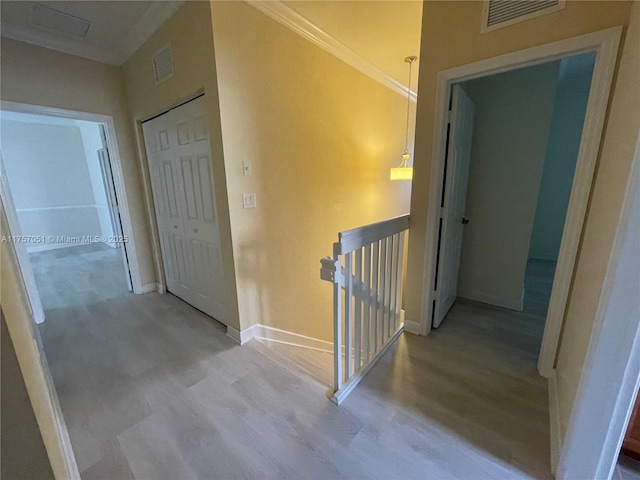 hall with visible vents, wood finished floors, an upstairs landing, and baseboards