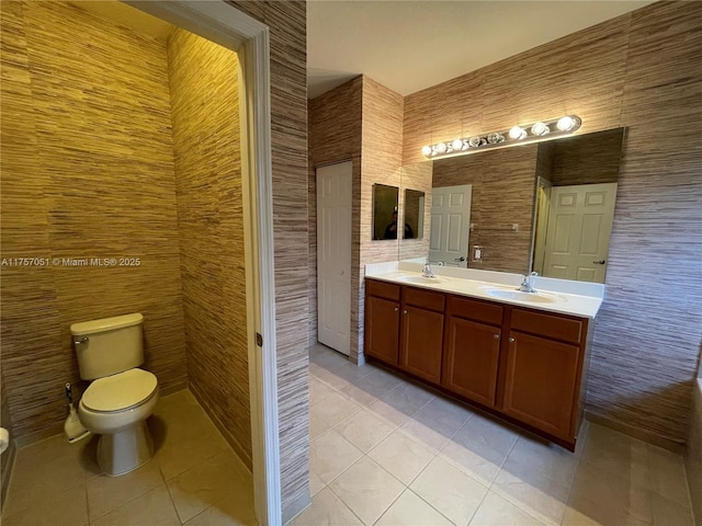 full bath featuring toilet, tile patterned flooring, double vanity, and a sink