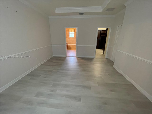 spare room with baseboards, ornamental molding, a raised ceiling, and wood finished floors