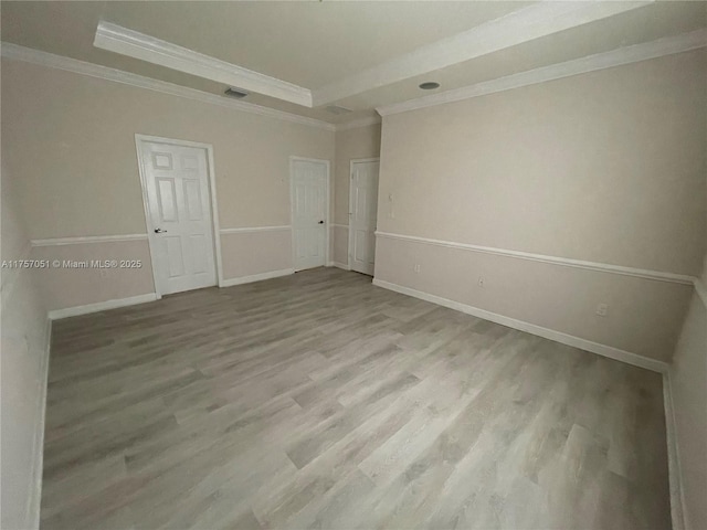 spare room with ornamental molding, wood finished floors, visible vents, and baseboards