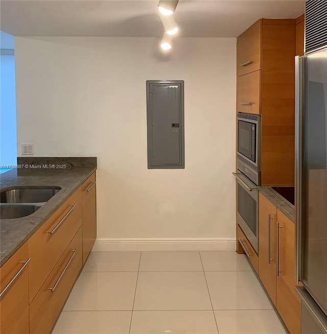 kitchen featuring light tile patterned flooring, stainless steel appliances, baseboards, electric panel, and modern cabinets