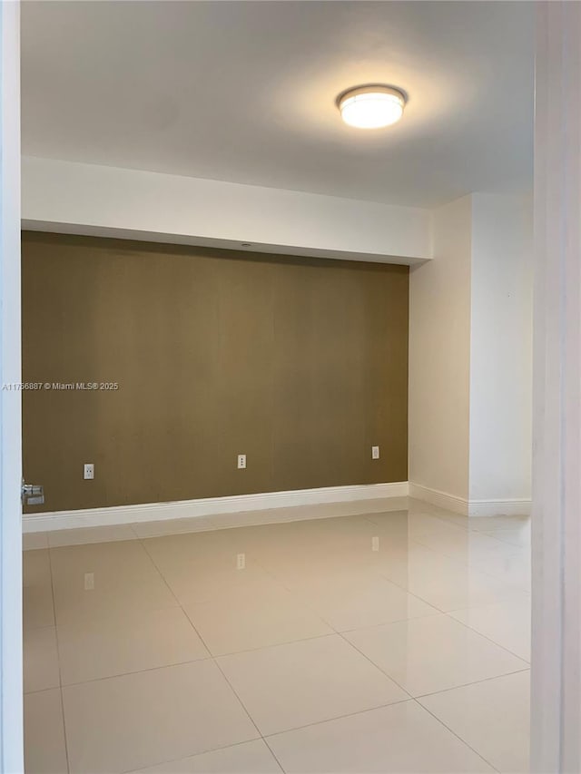 empty room featuring baseboards and light tile patterned flooring