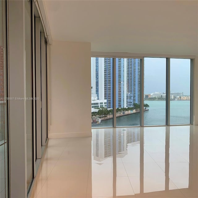 interior space featuring a city view, a wall of windows, a water view, and a healthy amount of sunlight