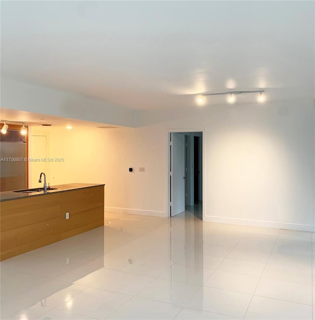 spare room with light tile patterned floors, a sink, and baseboards