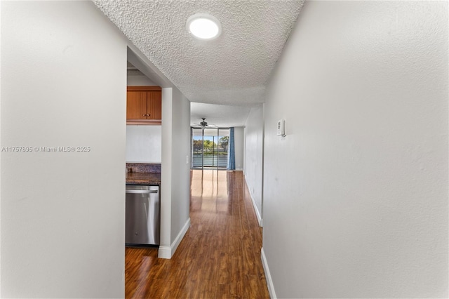 hall featuring baseboards, dark wood finished floors, and a textured ceiling