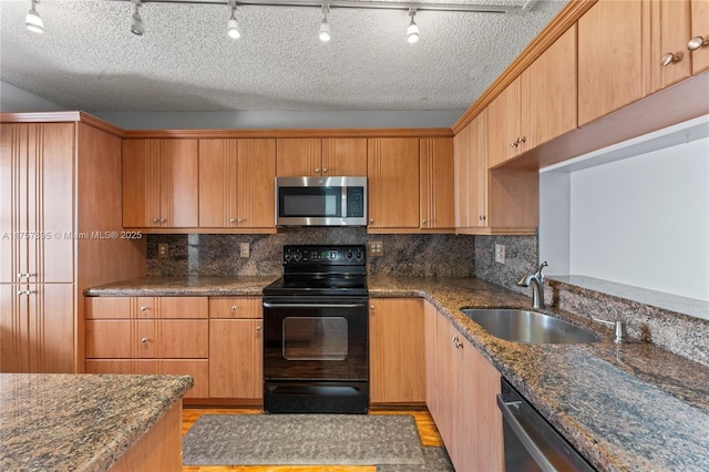 kitchen with backsplash, dark stone countertops, stainless steel appliances, and a sink