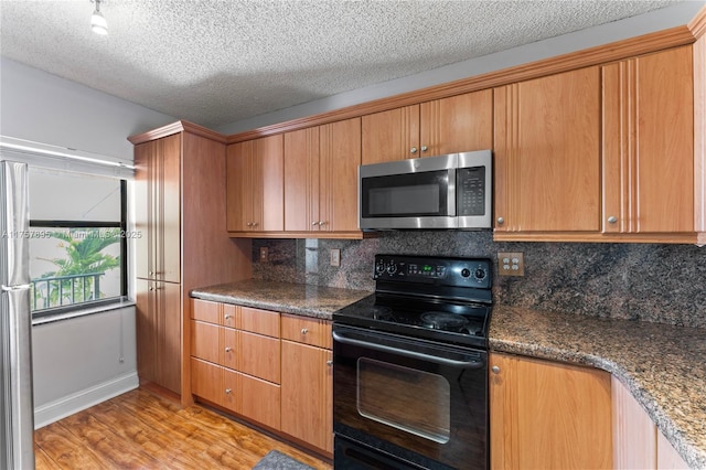 kitchen with tasteful backsplash, light wood-style flooring, stainless steel microwave, black electric range oven, and a textured ceiling