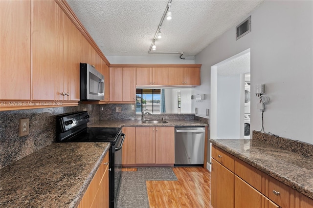 kitchen with visible vents, decorative backsplash, appliances with stainless steel finishes, stacked washing maching and dryer, and a sink