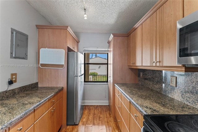 kitchen featuring electric panel, decorative backsplash, appliances with stainless steel finishes, a textured ceiling, and light wood-style floors