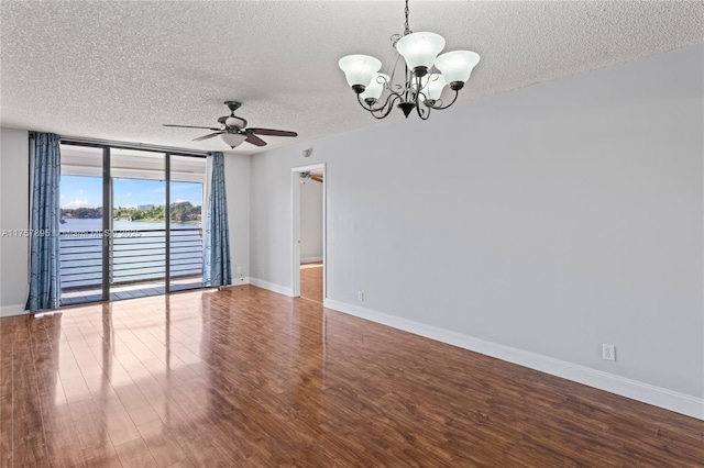 spare room with a textured ceiling, ceiling fan with notable chandelier, a water view, wood finished floors, and baseboards