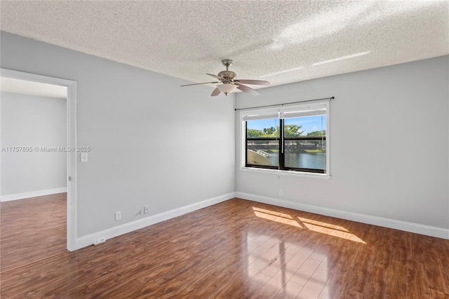 empty room featuring ceiling fan, a textured ceiling, baseboards, and wood finished floors