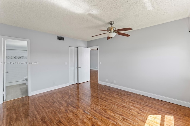 unfurnished bedroom with visible vents, a textured ceiling, baseboards, and wood finished floors