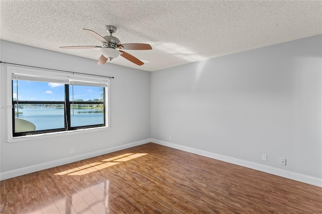 spare room featuring a ceiling fan, a textured ceiling, baseboards, and wood finished floors