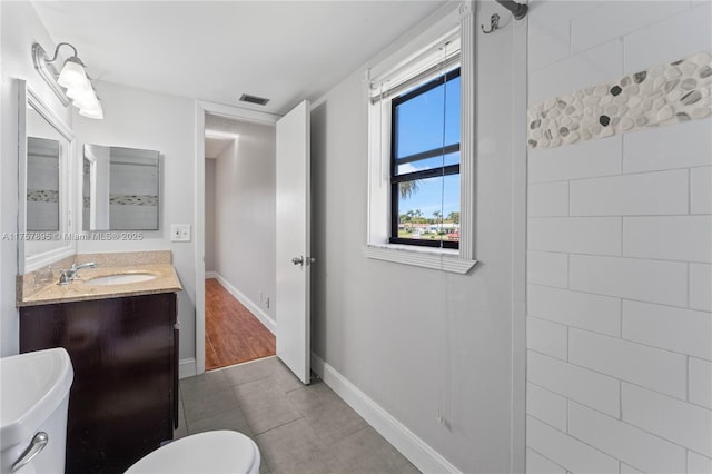 bathroom with toilet, vanity, visible vents, baseboards, and tile patterned floors