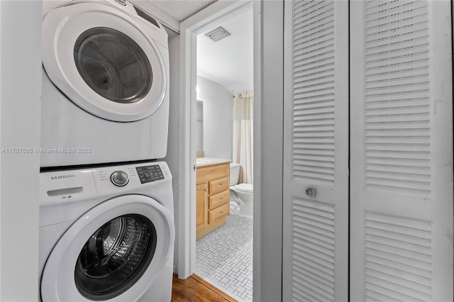 clothes washing area with stacked washer / dryer, laundry area, and visible vents