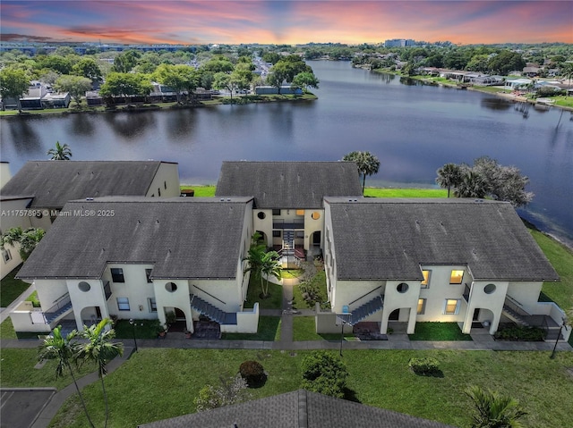 aerial view at dusk featuring a water view