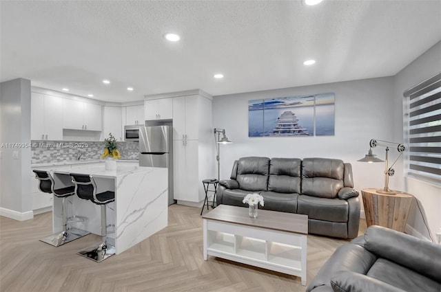 living room with recessed lighting, a textured ceiling, and baseboards