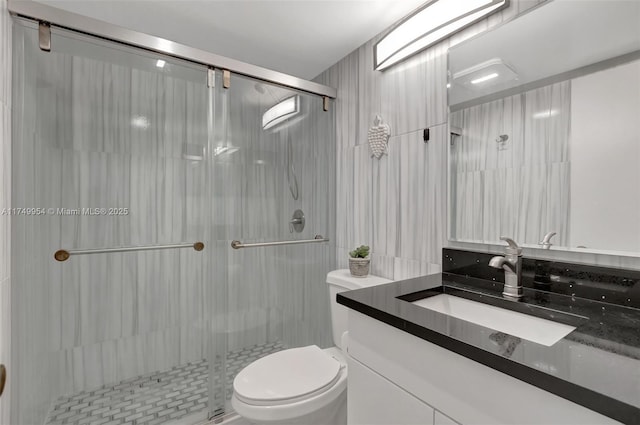 full bath with tile walls, a shower stall, toilet, and vanity