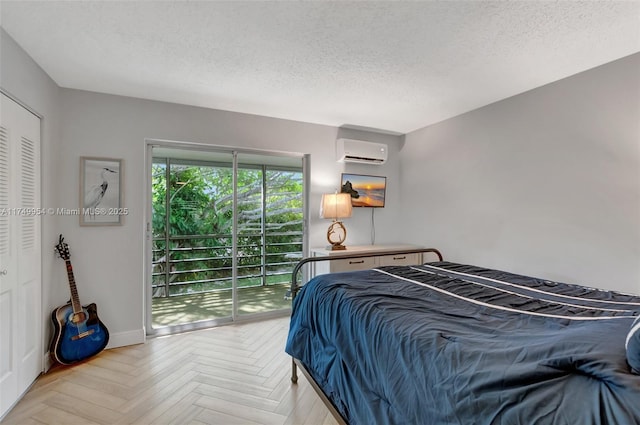 bedroom featuring access to exterior, baseboards, a textured ceiling, and a wall mounted air conditioner