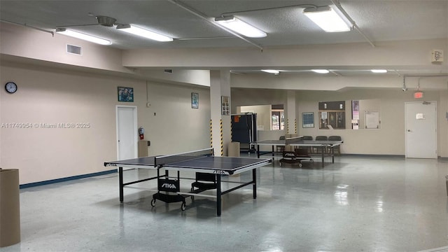 recreation room featuring baseboards, visible vents, and a textured ceiling