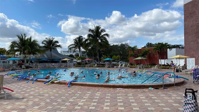 community pool with a patio area and fence