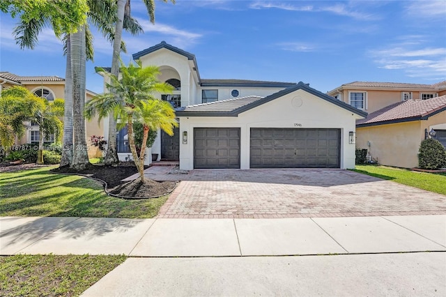 view of front of property featuring a garage, a front yard, decorative driveway, and stucco siding