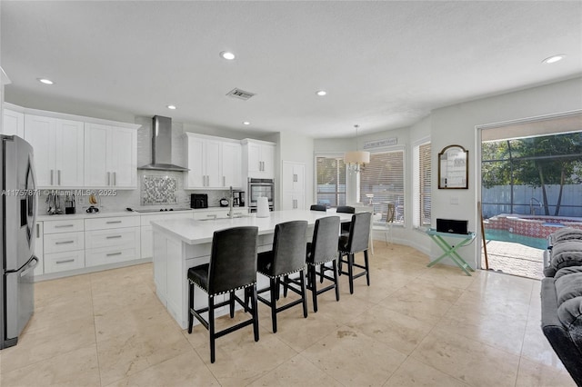 kitchen featuring black electric cooktop, visible vents, stainless steel refrigerator with ice dispenser, wall chimney exhaust hood, and tasteful backsplash