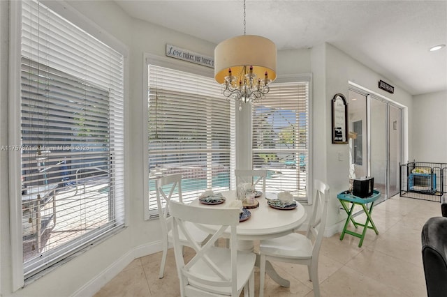 dining space with a chandelier, baseboards, and light tile patterned floors