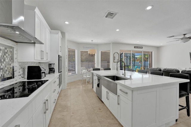 kitchen with black electric stovetop, a sink, visible vents, backsplash, and wall chimney exhaust hood