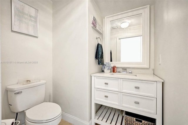 bathroom featuring toilet, baseboards, and vanity