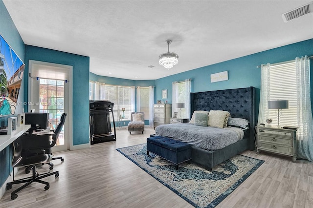 bedroom featuring a chandelier, access to outside, wood finished floors, and visible vents