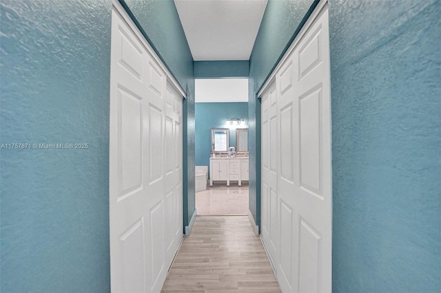 hall with light wood-style floors and a textured wall